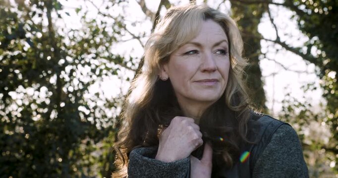 Attractive happy middle aged woman in her forties outside thoughtful, sad or depressed in golden winter sunshine