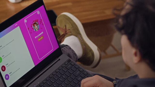 Over shoulder view of unrecognizable man swiping right and left while searching for perfect match, laptop placed on his laps