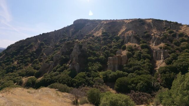 A breathtaking view of Kula fairy chimneys  by vibrant greenery under a bright sky, depicting nature's wild beauty and the awe-inspiring formations of the earth.
