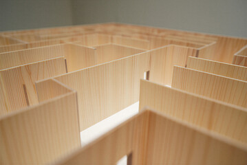 Wooden isometric design segment of maze with vertical grain texture against gray wall