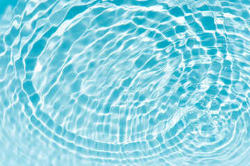 Bluewater waves on the surface ripples blurred. Defocus blurred transparent blue colored clear calm water surface texture with splash and bubbles. Water waves with shining pattern texture background.