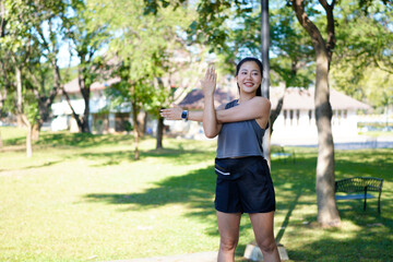 Obraz premium Happy female athlete stretching while warming up for sports training outdoors