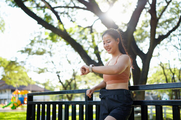 Naklejka premium Young woman checking time on smartwatch while exercising outdoors. Concept of fitness tracking, workout routine, health monitoring, and active lifestyle with wearable technology.