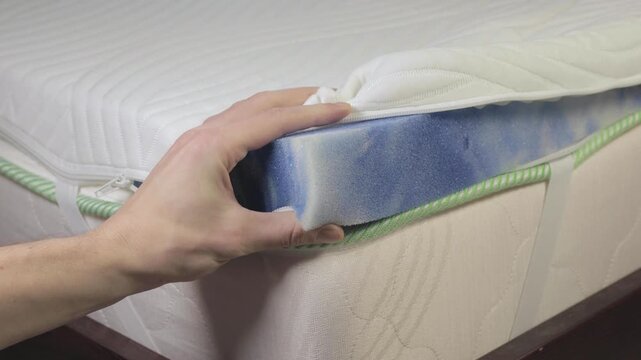 Man checking the softness of the filling of a memory foam mattress. 