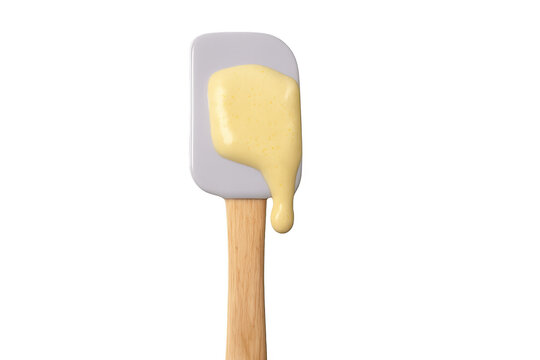 Silicone spatula holding dripping yellow batter on transparent background