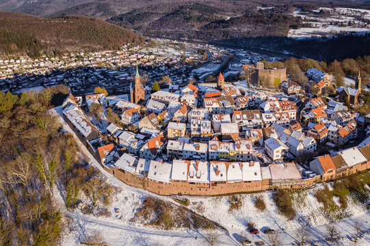 Aerial view of snow-dusted rooftops and ancient walls bask in the winter sun, Burgfeste Dilsberg stands guard, Neckargemund, Baden-Wurttemberg, Germany.