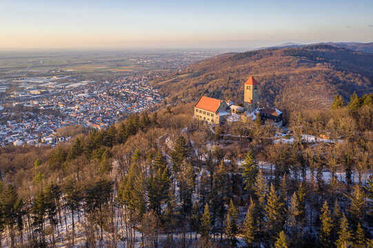 Aerial view of Windeck Castle perched atop a wooded hill, overlooking the town below under the soft glow of sunset, Weinheim, Baden-Wurttemberg, Germany.