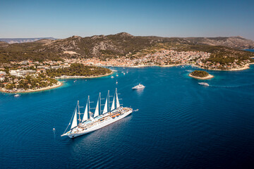Aerial view of a majestic tall ship sailing on the azure waters near the historic cityscape, framed by rugged mountains, Split, Split-Dalmatia County, Croatia.