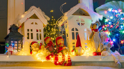 Christmas view from a white cardboard house, various gnome figures, colorful lights, home interior decor, festive mood