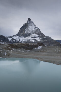 Aerial view of the iconic Matterhorn peak piercing the sky, reflected in the serene turquoise lake below, Trockener Steg, Valais, Switzerland.