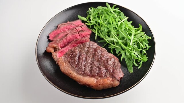Cooking steak with arugula on a plate showing the process of preparing and plating the meal in a kitchen setup