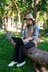 Asian adult botanist researcher conducts ecological field research uses laptop computer exploring nature habitat for scientific study