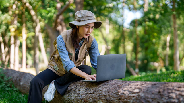 Asian adult woman biologist explorer works laptop research plant data nature study sustainable ecology environmental science investigation