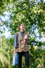Asian botanical researcher woman conducts fieldwork exploring lush green forest environment for plant study ecology science discovery