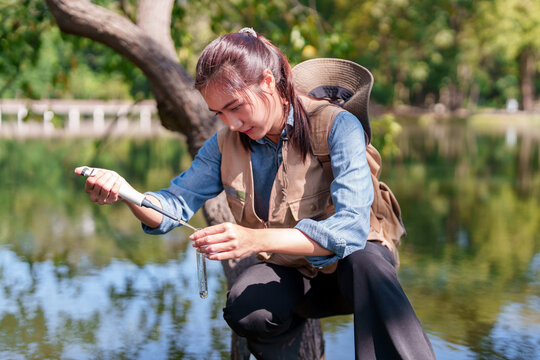 Asian adult woman botanist researcher tests water quality outdoor natural habitat environmental study ecological data collection scientific investigation