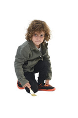 Front view of a kneeling child looking at a camera and painting with a brush on white background