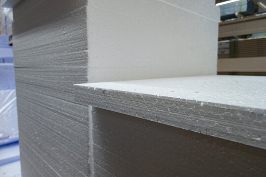Close-up view of stacked white foam boards in a warehouse during daylight showing texture and edges of material