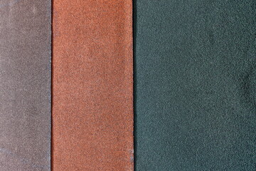 Fototapeta premium Different colors of sandpaper laid out side by side on a flat surface for viewing texture and material properties in a workspace setting