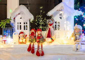 Christmas view from a white cardboard house, various gnome figures, colorful lights, home interior decor, festive mood