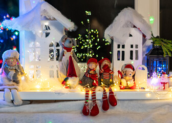 Christmas view from a white cardboard house, various gnome figures, colorful lights, home interior decor, festive mood