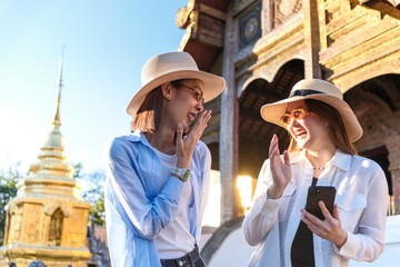 Two beautiful asian women are laughing and having fun during their trip in Thailand, admiring...