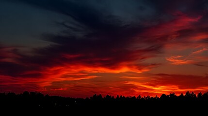Dramatic sunset ablaze with fiery hues above silhouetted trees. A stunning, natural spectacle