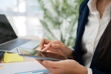 Digital Workspace Interaction: A business professional hands expertly navigate a digital tablet within a contemporary office environment, suggesting productivity and modern business practices.