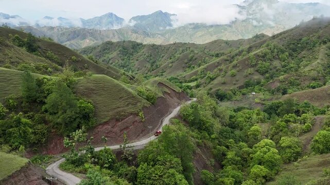 Aerial view of car driving through the fores and the lake on the side. Beautiful mountain road. Driving on the mountain road. Road trip. Mountain forest lake landscape. Car driving through pine forest
