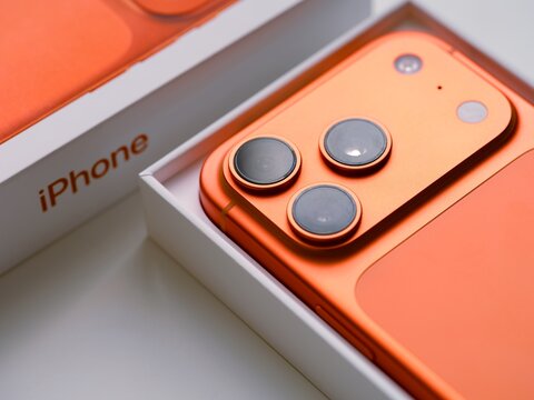 Tambov, Russian Federation - December 14, 2025 A close-up of an open box with new Apple iPhone 17 Pro smartphone in the cosmic orange color on white background.