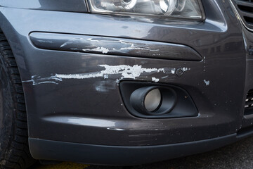 Scratched or grazed car side fender or bumper with damaged paint job after minor accident. Low angle, close up shot, no people