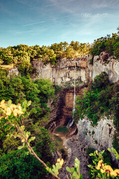 Aerial view of a delicate waterfall cascading down rugged cliffs into a serene pool, embraced by vibrant greenery, Pican, Istria County, Croatia.