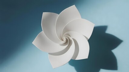 White paper flower with spiral design casting a shadow on a blue background