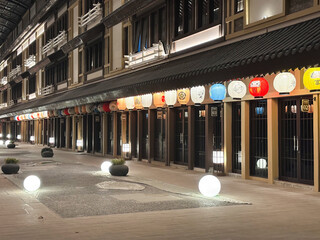 corridor featuring traditional Japanese architecture (Machiya style) at night. The scene is characterized by a long row of multi-story wooden buildings
