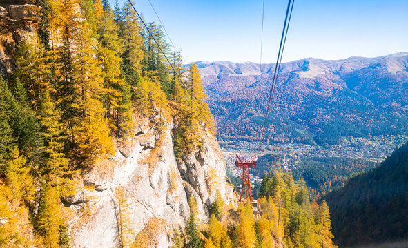Cable car line in rocky autumn mountain landscape with golden larch trees, Bucegi Mountains, Romania