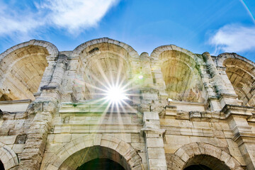 Arches of the Roman arena of Arles crossed by beautiful rays of sun in France.