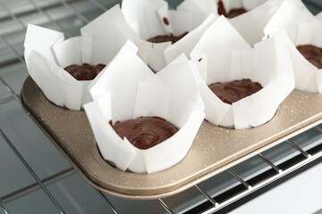 Tasty chocolate muffins baking in oven, closeup