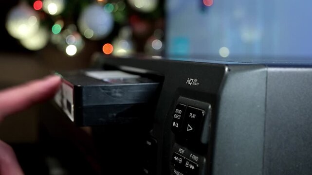 man inserting a video tape into video tape player