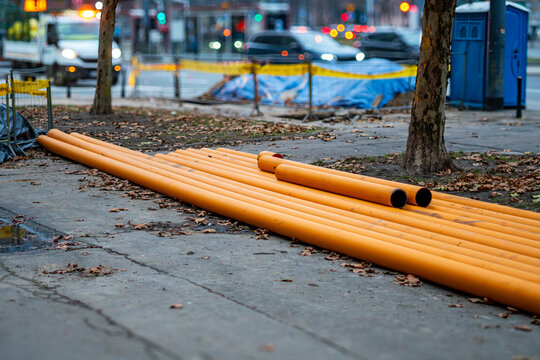 Orange utility pipes laid on sidewalk in Warsaw, urban infrastructure during street construction works in city center