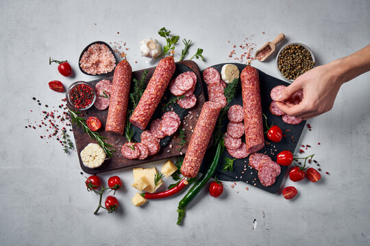 Hand picking sliced salami from charcuterie board - Powered by Adobe