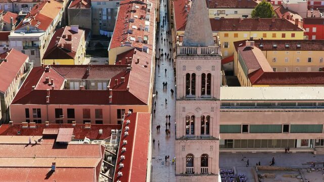 Aerial drone view of the bell tower of St. Anastasia's Cathedral and Zadar's famous marble street, Kalelarga, lined with traditional Mediterranean buildings and red tiled roofs