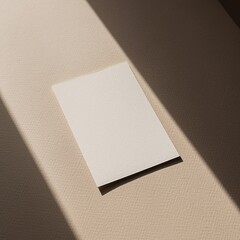 Blank textured card mockup on beige surface with natural sunlight shadow