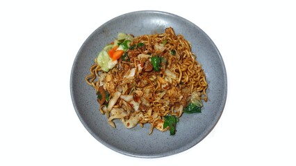 Delicious Indonesian Fried Noodles or Mie Goreng with Pickles and Vegetables Served on a Plate Isolated on White Background