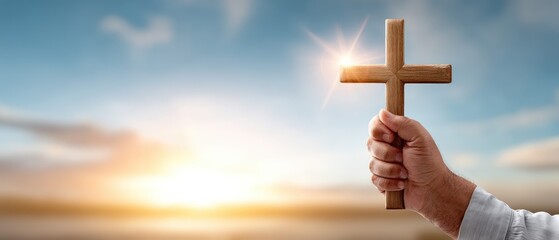 Hand holds wooden cross against colorful sunset sky with space for text showcasing a Christian theme and reflection moment