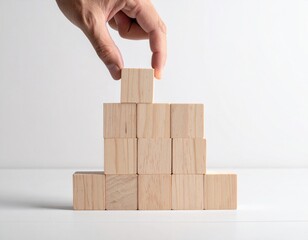 Hand stacking wooden blocks to build a pyramid shape on a white background