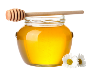 Glass honey pot with wooden dipper isolated on white