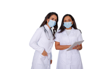 Two female doctors or nurses wearing face masks and white lab coats, using a digital tablet and collaborating