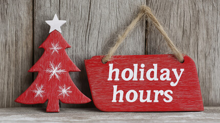 Red and white wooden "Holiday Hours" sign and Christmas tree decoration against a weathered wood wall