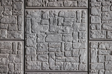 Abstract geometric pattern of grey brick and stone squares on wall.