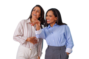 Happy business women friends laughing and smiling, pointing away with a feeling of joy and connection