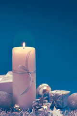 Advent candle with Christmas decoration isolated on blue background.